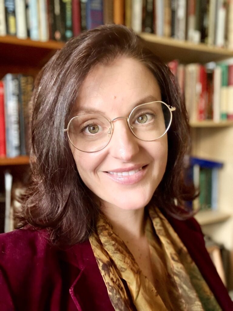 Image of Nicoletta, a woman with dark hair, glasses and a welcoming smile.